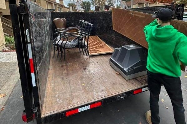 Blog 3 a man standing in the back of a truck with furniture