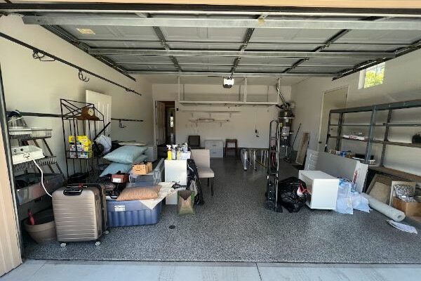 a room with a garage door and a shelf with luggage