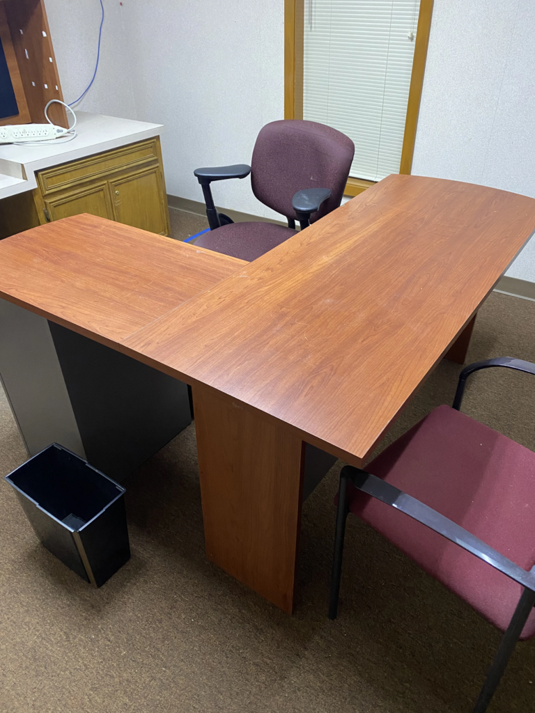 a desk with chairs and a trash can